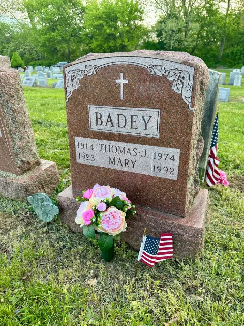 American flag and pink arrangement at a family headstone