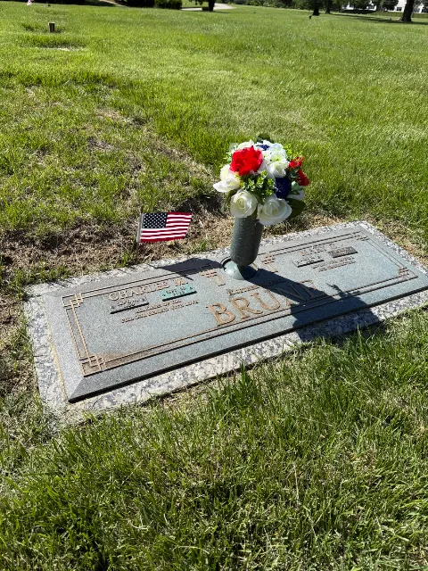 American flag and arrangement at a flat grave marker